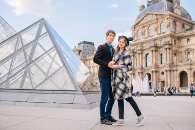 Louvre Sarayı ve Louvre Piramidi önünde aşık turistler. Louvre dünyanın en büyük ve en çok ziyaret edilen müzelerinden biridir..
