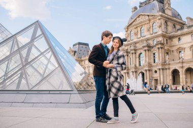 Louvre Sarayı ve Louvre Piramidi önünde aşık turistler. Louvre dünyanın en büyük ve en çok ziyaret edilen müzelerinden biridir..