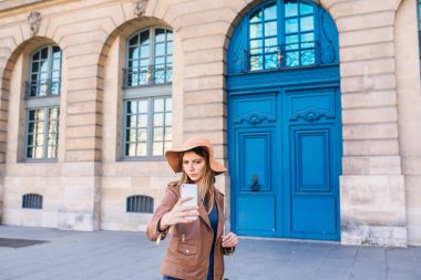 Şapkalı güzel bir kadın mavi bir antika kapının önünde duruyor. Paris, Fransa