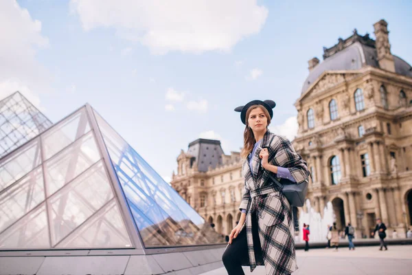 ルーブル美術館の近くに美しいコートを着た女の子が立っています フランスと歴史的建造物の訪問の概念 — ストック写真