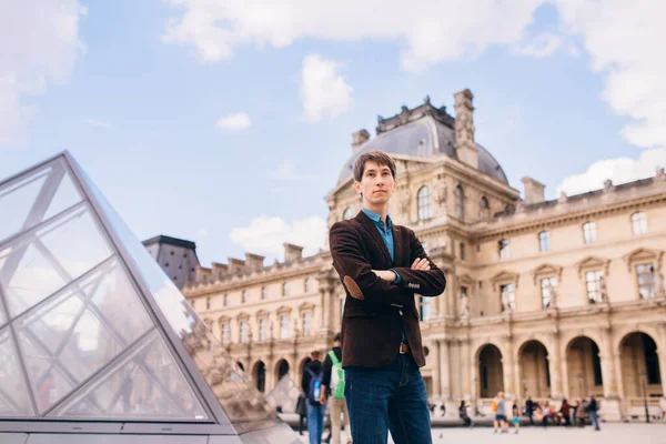 Louvre binasının arka planında genç bir adam duruyor. Paris, Fransa