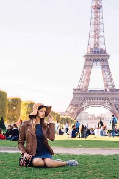 美丽的女孩坐在巴黎埃菲尔铁塔的背景下 — 图库照片