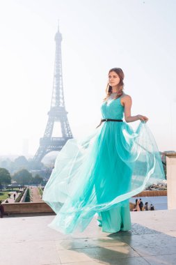 Paris 'te yeşil elbiseli bir kız yazın Trocadero meydanındaki Eyfel kulesinin arka planında zarif bir Fransız kadınının lüks ve güzel bir figürü..