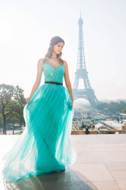 Paris 'te, arka planında Eyfel kulesi olan, gök mavisi bir gece elbisesi içinde güzel bir kız. Fransa.