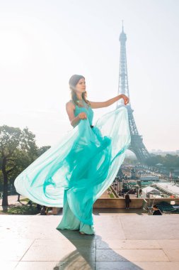 Paris 'te, arka planında Eyfel kulesi olan, gök mavisi bir gece elbisesi içinde güzel bir kız. Fransa.