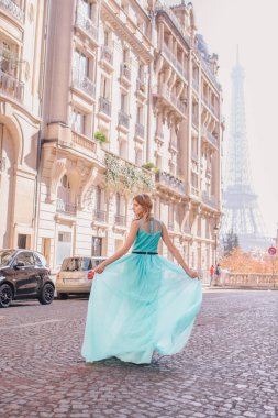 Paris 'teki Eyfel Kulesi manzaralı, sokakta elbise giymiş güzel bir genç kız.