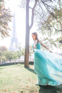 Paris 'te, arka planında Eyfel kulesi olan, gök mavisi bir gece elbisesi içinde güzel bir kız. Fransa.