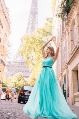 Paris 'teki Eyfel Kulesi manzaralı, sokakta elbise giymiş güzel bir genç kız.
