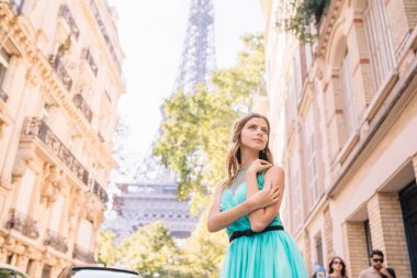 Paris 'teki Eyfel Kulesi manzaralı, sokakta elbise giymiş güzel bir genç kız.