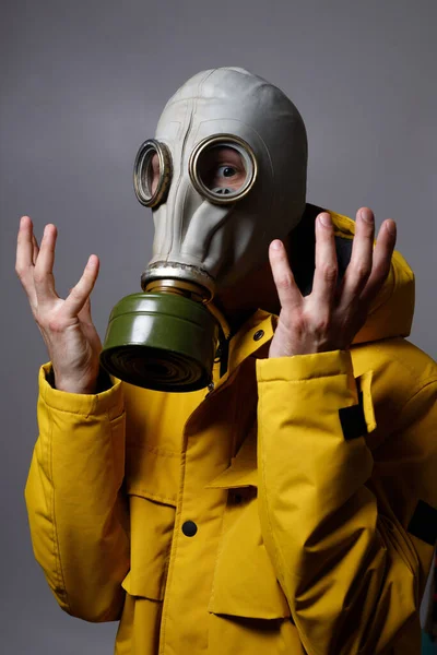 a man in a gas mask to resist the COVID-19 virus. raising his hands as a stop signal