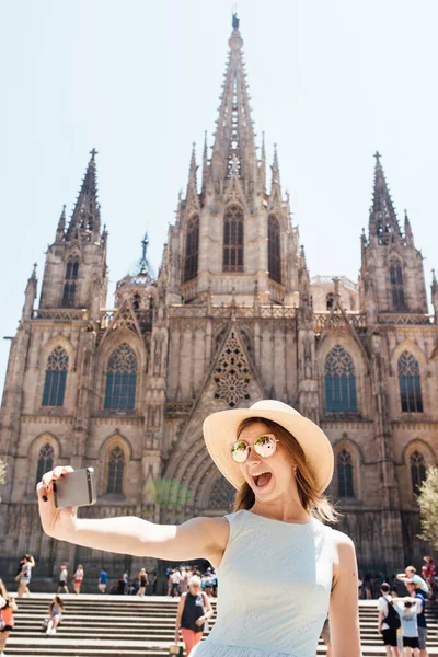 Genç ve mutlu bir turist Kutsal Üçlü Barselona Katedrali 'nin önünde selfie çekiyor.