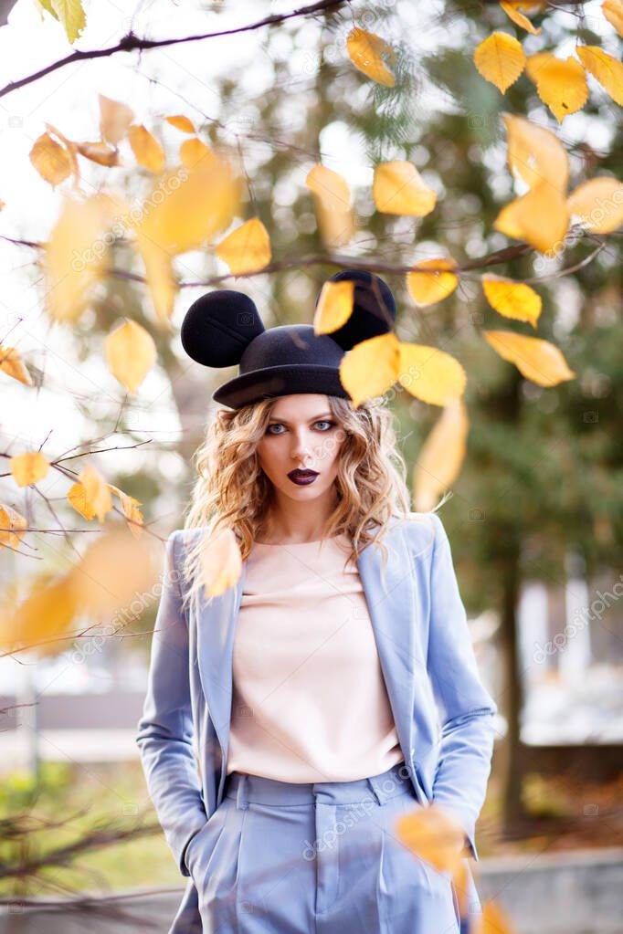 Cute girl on the street in a funny hat. Autumn leave. The Ears Of Mickey Mouse.