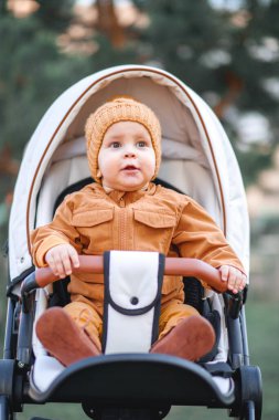 Sevimli, güzel bir çocuk bir bebek arabasında oturuyor ve gülümsüyor ve annesini bekliyor.