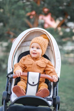 Sevimli, küçük, güzel bir çocuk bebek arabasında oturup annesini bekliyor.
