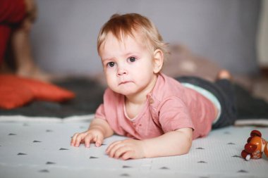 Odanın arka planında pembe tişörtlü bir bebeğin duygusal portresi.