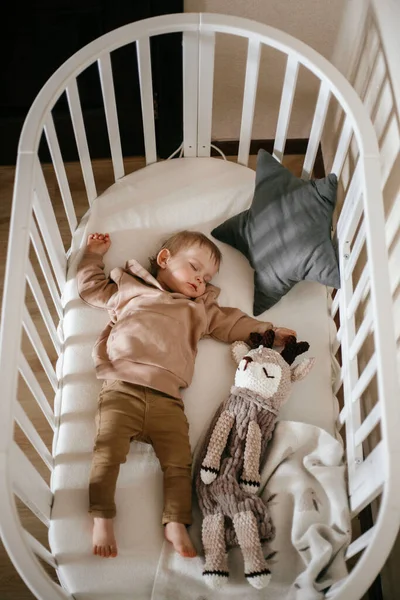 Sevimli, 1 yaşında bir bebek bir karyolada yatarken yüzünde ışık pencereleri, gündüz uyku konseptiyle uyuyor.