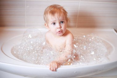 Banyoda su ve köpükle oynayan komik çocuk. Küçük çocuk banyo yapıyor..