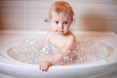 Banyoda su ve köpükle oynayan komik çocuk. Küçük çocuk banyo yapıyor..