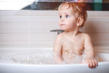 Banyoda su ve köpükle oynayan komik çocuk. Küçük çocuk banyo yapıyor..