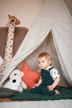 Bebek odasında golf arabasıyla oynuyor, yeşil bir tulum giymiş..