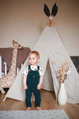 Bebek odasında golf arabasıyla oynuyor, yeşil bir tulum giymiş..