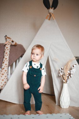 Bebek odasında golf arabasıyla oynuyor, yeşil bir tulum giymiş..