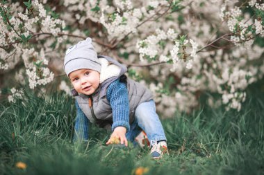 Çiçek açan ağaçlarla bahçede bir çocuk yürüyor. Bahar nefesi