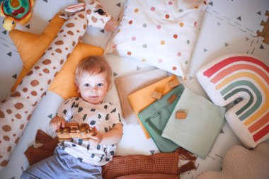 Mutlu bebek çocuk, çocuk odasında yerde duran tahta bir oyuncak arabayla oynuyor.