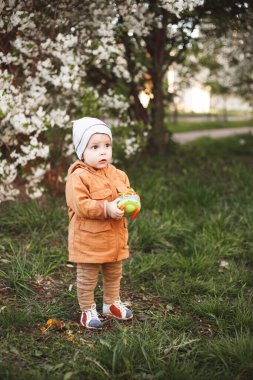 Çiçek açan ağaçlarla bahçede bir çocuk yürüyor. Bahar nefesi