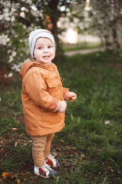 Çiçek açan ağaçlarla bahçede bir çocuk yürüyor. Bahar nefesi