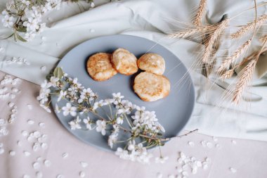 Bahar sağlıklı kızarmış peynirli kekler, çiçek açan beyaz çiçeklere karşı.
