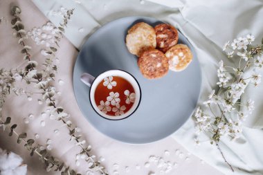 Sabah kahvaltısı, kızarmış güzel peynirli kekler, masa örtüsünün üstünde, bahar çiçeğinin yanında.