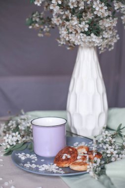 Sabah kahvaltısı, kızarmış güzel peynirli kekler, masa örtüsünün üstünde, bahar çiçeğinin yanında.