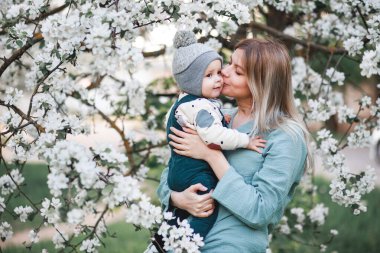 Bir kız ve oğlu baharda çiçek açan elma ağacının yanında.