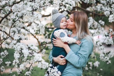 Bir kız ve oğlu baharda çiçek açan elma ağacının yanında.