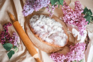Ev yapımı elmalı turta bir kase leylağın yanındaki ahşap masada. Yumuşak tonlama. Seçici odak.