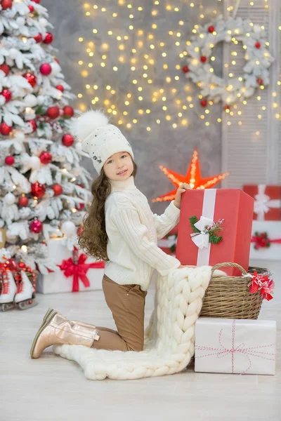 Weihnachtsfeier. niedliches kleines Mädchen in einem schönen Kleid, das in der Nähe des Weihnachtsbaums sitzt. Weihnachtswunder. Luxuriöse Weihnachtsdekoration. — Stockfoto