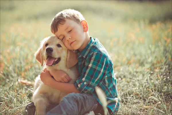 驚くべき白ピンク ラブラドル ・ レトリーバー犬子犬完全ちからと夏の晴れた日の休暇の週末を楽しんで遊んで屋外青い目を持つ十代のかわいいハンサムな男の子。親友と満足の笑みを浮かべて子供 — ストック写真