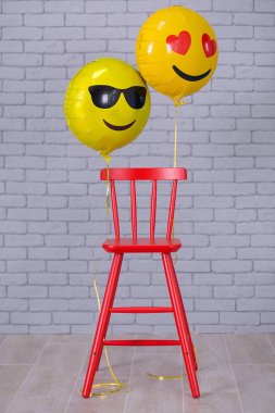 Sandalye, tuğla duvar, sarı ayrıntıları balonlar emoji kırmızı sandalye ile gri daire studio