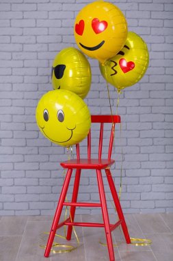 Sandalye, tuğla duvar, sarı ayrıntıları balonlar emoji kırmızı sandalye ile gri daire studio