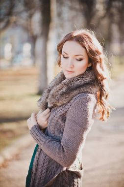 Gizemli güzel genç esmer Bayan portre sevimli yüz ve profesyonel olarak oturmak rahat sıcak tasarımcı kürk ile sonbaharda kıyafetlerle kamera için poz ayartma dudakları ile bahar central park