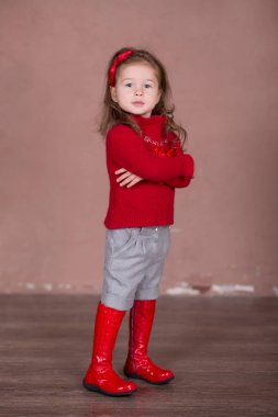 Şık brunnete saçlı güzel kız happyly photosession bebek botları modern showroom Studio için kamera için poz gülümseyen kırmızı kazak kazak sıcak kış şort pantolon giymiş.
