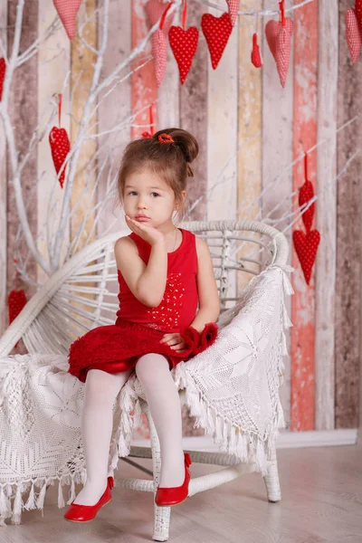 Joven morena dolly lady girl elegante vestido con zapatos de correa de vestido rojo sonriendo posando sentado en el estudio y sosteniendo gran corazón enorme con labios de puchero y mejillas rosadas . —  Fotos de Stock