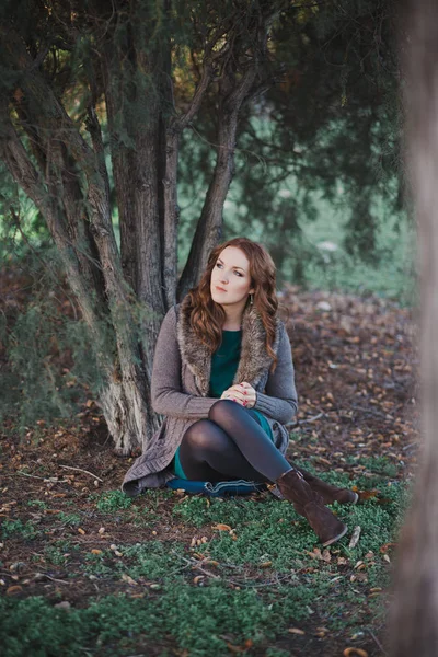 秋の暗い森の首孤独なポーズ座ってカメラのために毛皮をスタイリッシュな暖かい服に身を包んだ美しい本物女性ブルネット巻き毛と愛らしい目で神秘的です — ストック写真