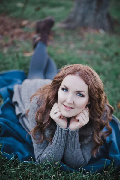 Sensuale signora bruna con labbra rosa broncio e guance bianche che indossano casual accogliente maglione con pelliccia posa sit for su erba verde in autunno foresta Central Park — Foto Stock