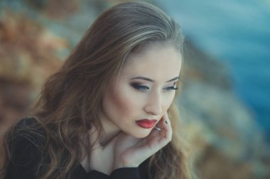 Romantik pout kırmızı dudaklar ve şık ceket giymiş pembe yanakları ile baştan çıkarıcı seksi Bayan kız elbise ve şort ile sonbahar bot ile kayalık plaj deniz tarafında poz telafi yüzünde ben romantik bölüm