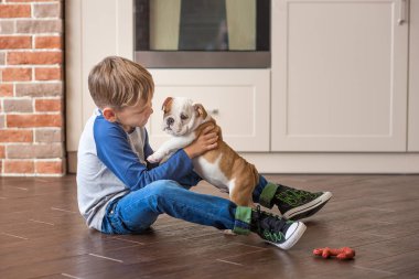 Sevimli çocuk köpek yavrusu İngilizce bulldog ile oynamak