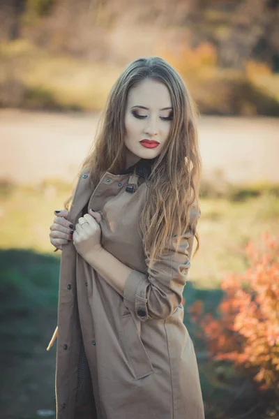 Sexy incroyable dame fille nifty élégant habillé en veste d'automne avec des cheveux blonds et les lèvres rouges de coulis avec maquillage visage posant assis pour caméra dans le parc central prairie de forêt de printemps — Photo
