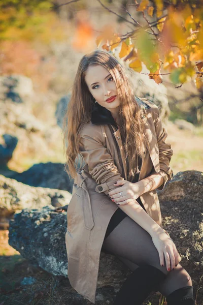 Sexy chica increíble chica ingeniosa elegante vestida con chaqueta de otoño con pelos rubios y pucheros labios rojos con maquillaje cara posando sentarse para la cámara en el parque central primavera bosque pradera — Foto de Stock