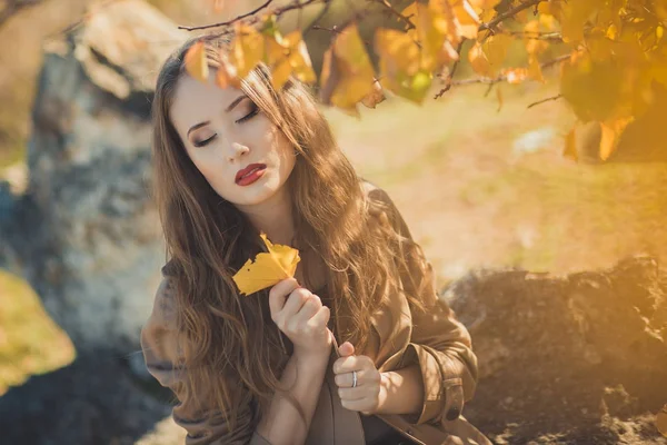 Sexy chica increíble chica ingeniosa elegante vestida con chaqueta de otoño con pelos rubios y pucheros labios rojos con maquillaje cara posando sentarse para la cámara en el parque central primavera bosque pradera — Foto de Stock